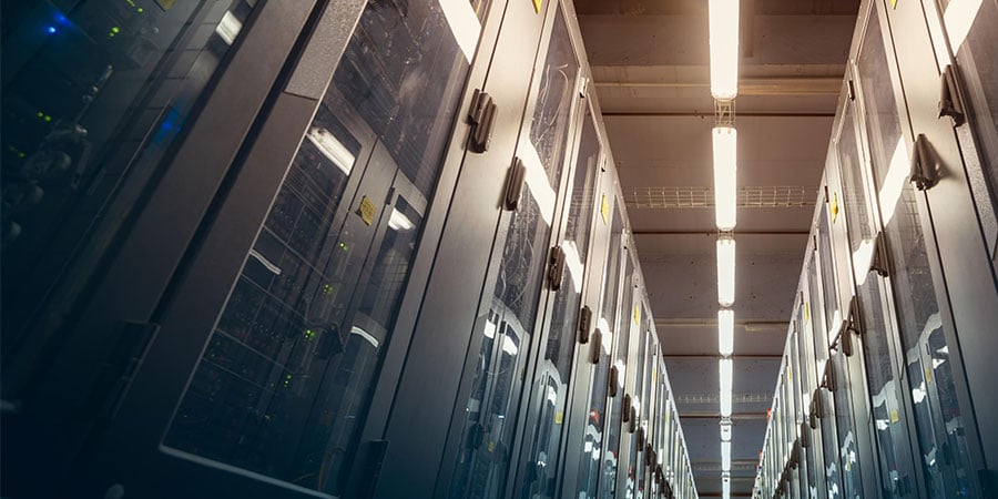Row of server racks in a modern data center with bright overhead lighting.