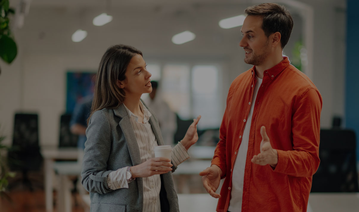 Man in red shirt and woman in gray blazer discussing in a brightly lit office, featured in promotional banner for E.ON Next case study.